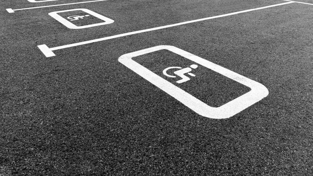 A crisp white accessible-parking symbol and stall lines painted on dark, new asphalt